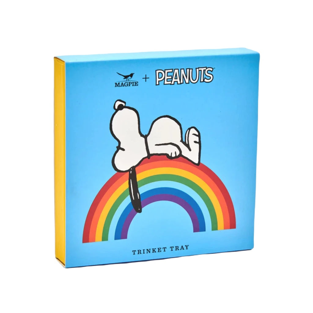 A blue box features a drawing of Snoopy lying on a rainbow, with text that reads "Magpie + Peanuts comic strip" at the top and "Good Vibes Trinket Tray" at the bottom.