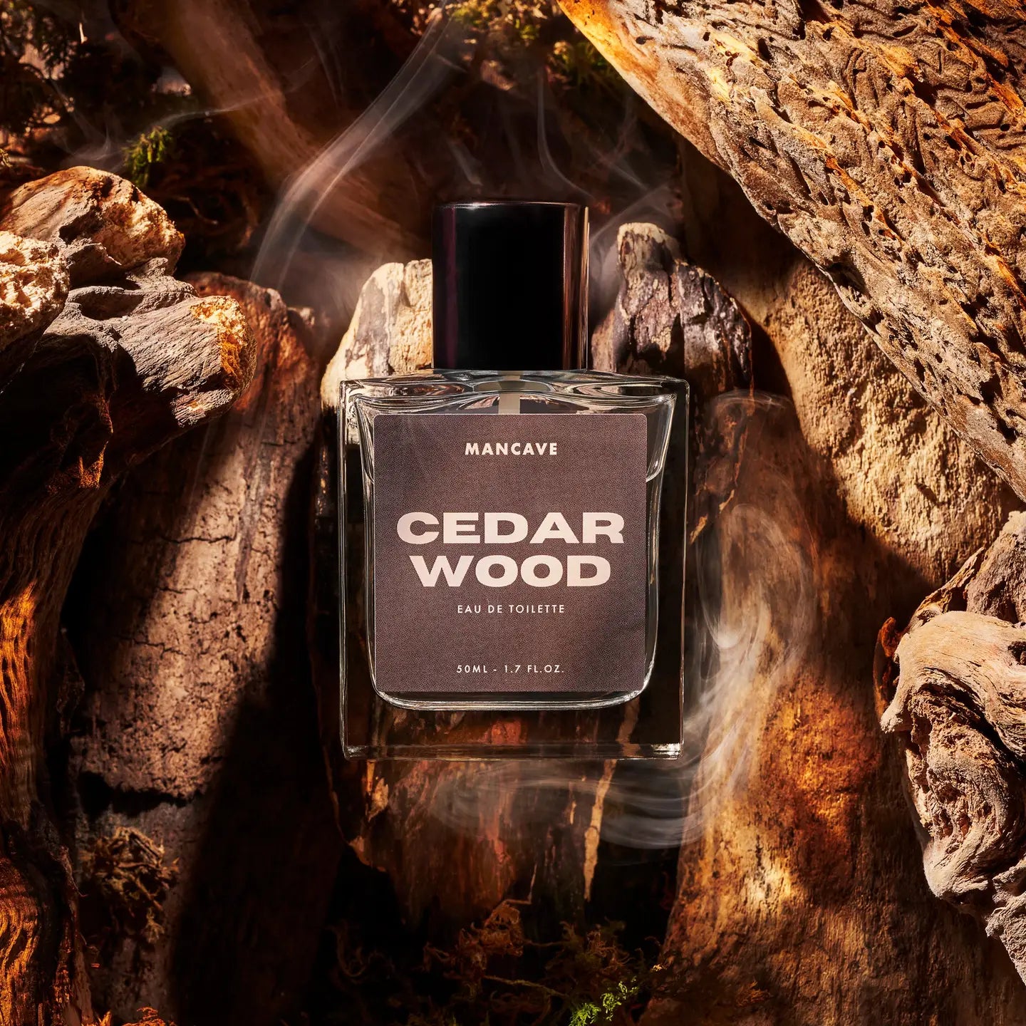 ManCave Cedarwood Eau De Toilette Spray 50ml bottle surrounded by cedarwood pieces, misty scent, premium men's fragrance.
