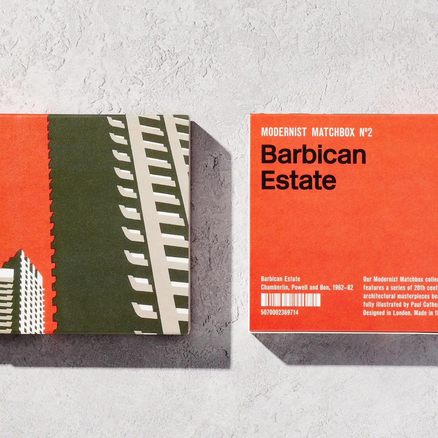 A box of matches called "Blue Crow Media Modernist Matchbox Barbican Estate," featuring an illustration by Paul Catherall, showcases modernist matchboxes inspired by 20th-century architecture. The cover displays a striking building, with some matches partially pulled out.