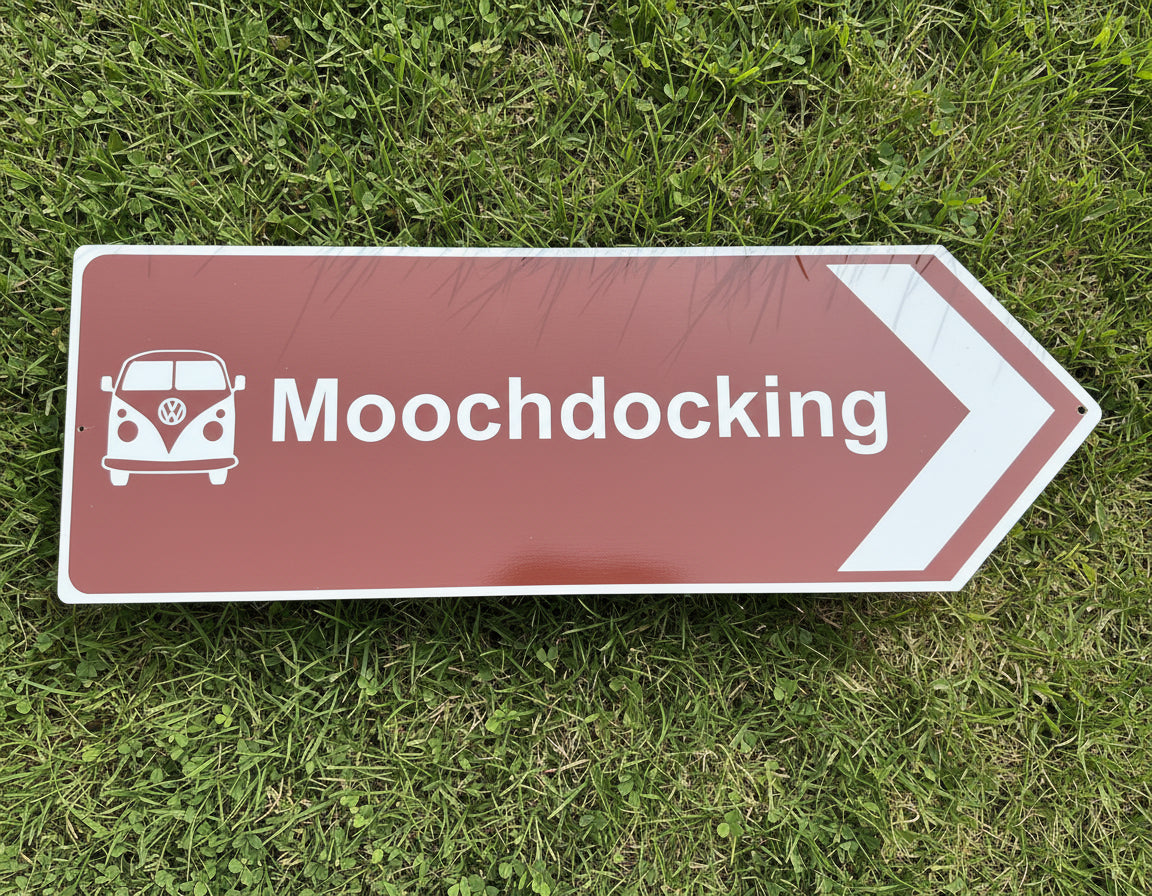 Directional sign pointing to 'Mooch docking' with a Volkswagen van icon on a grass background.