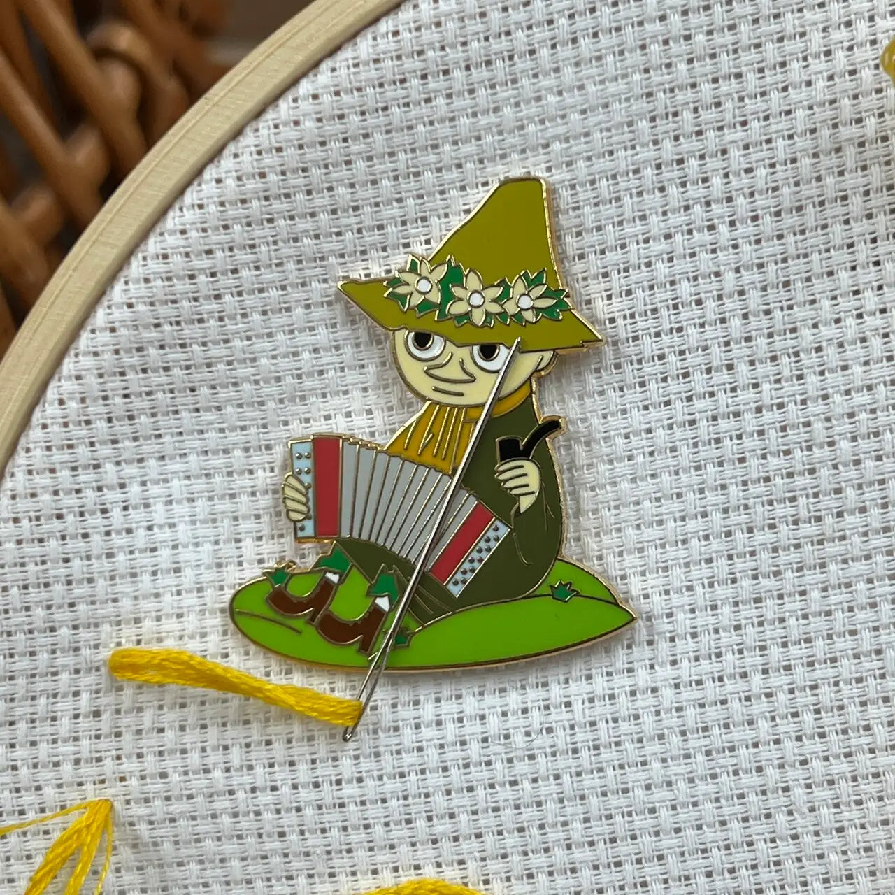 The Crafty Kit Co Moomin Needle Minder features a Little My character with a mischievous expression, dressed in red and holding a needle with pink thread. This charming embroidery accessory comes equipped with a strong magnet to keep your project secure.