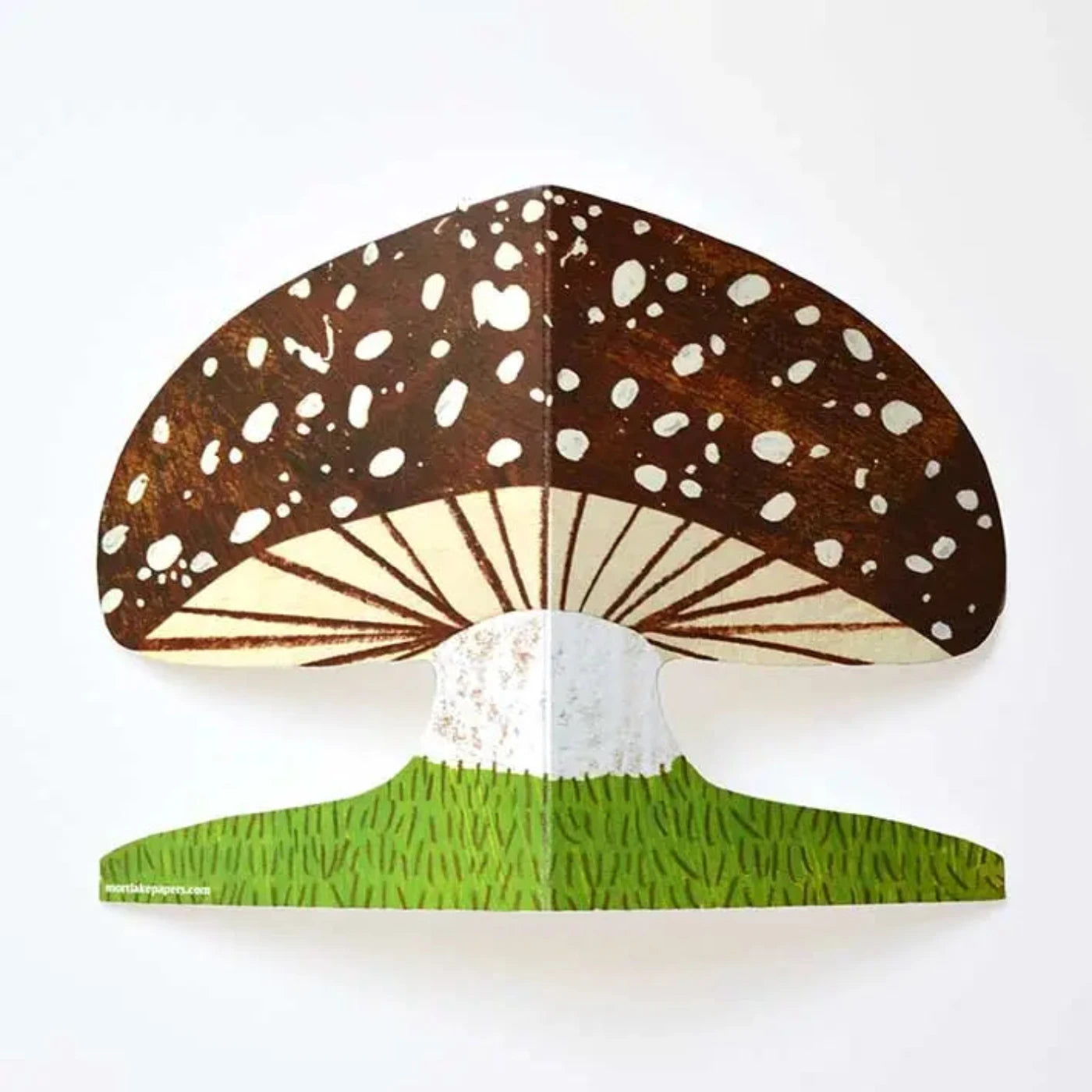 laid out mushroom shaped card with brown cap and spots growing from green grass at the bottom.