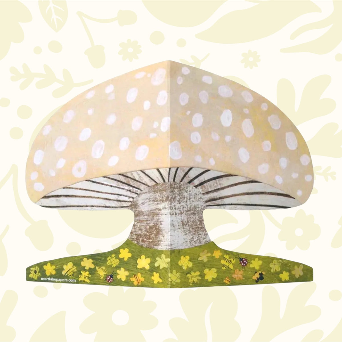 Up close image shows the details of the mushroom shaped greeting card with floral details, ladybirds.