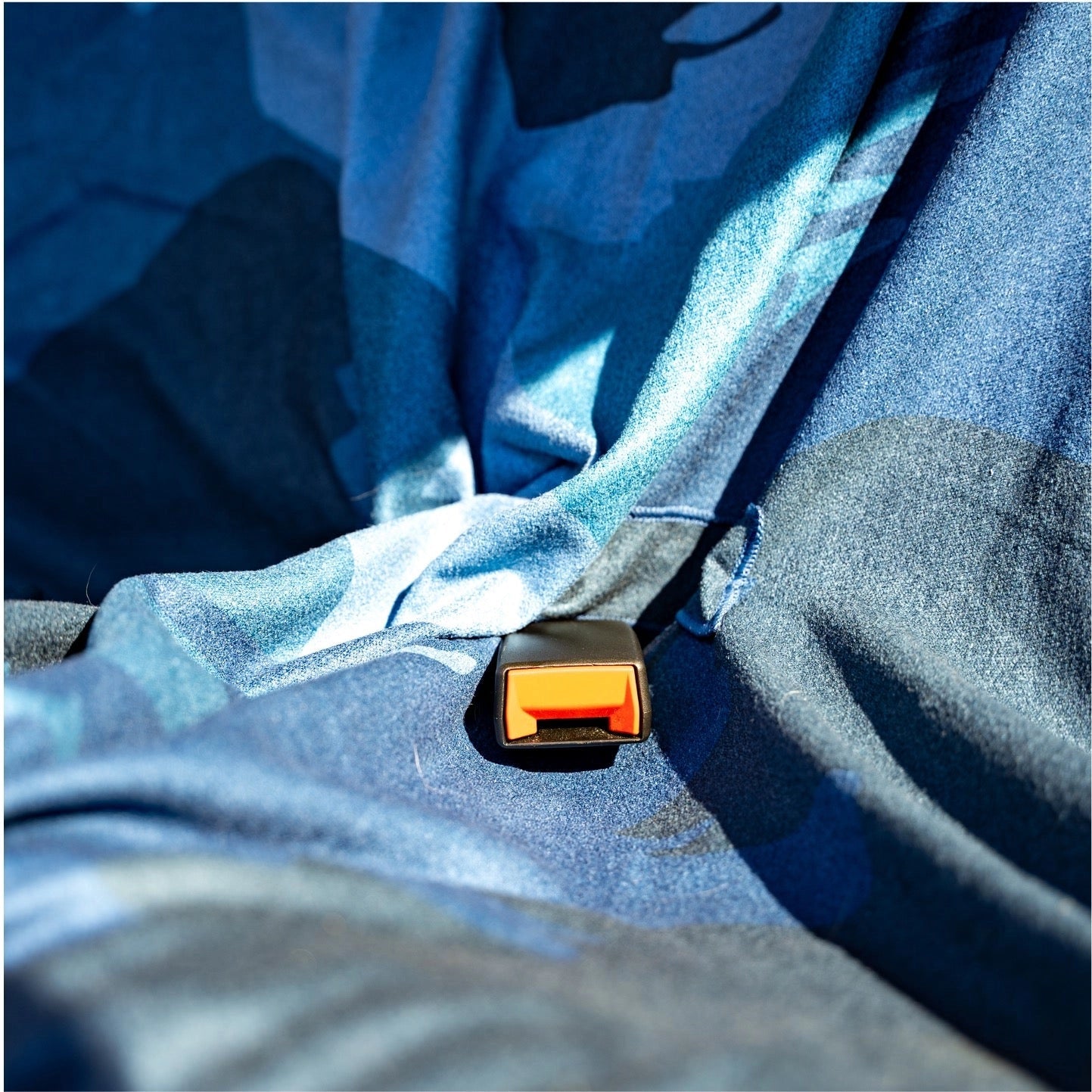 Forager Provisions LTD Sprints terry towel car seat cover with blue Bigfoot and moon print over a seat belt buckle