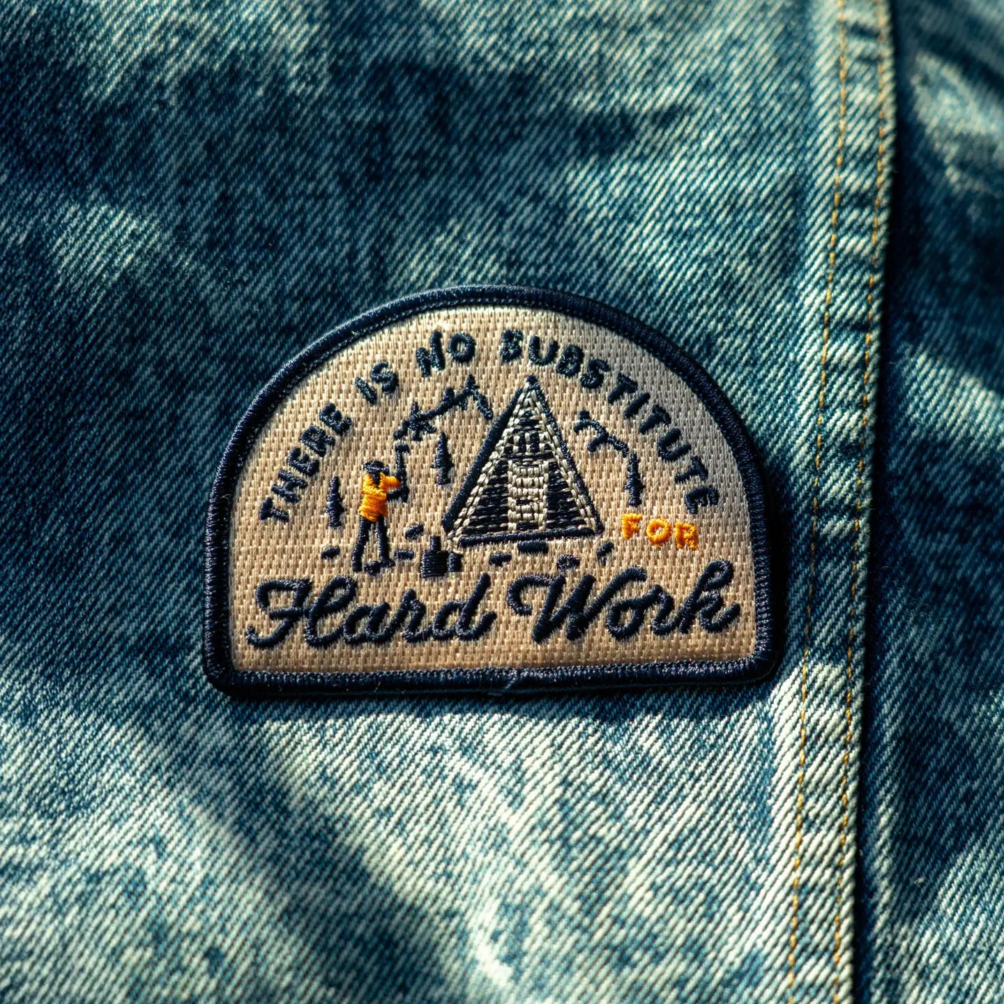 Denim jacket featuring Oxford Pennant patch embroidered with "There Is No Substitute For Hard Work" and log cabin design.