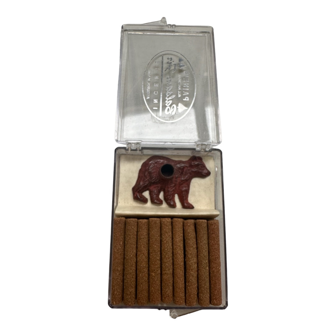 An open PAINES Brass Bear & Holder box displays eighteen balsam fir-scented logs and a red bear-shaped holder, exuding a forest aroma. The box lid is partially open.