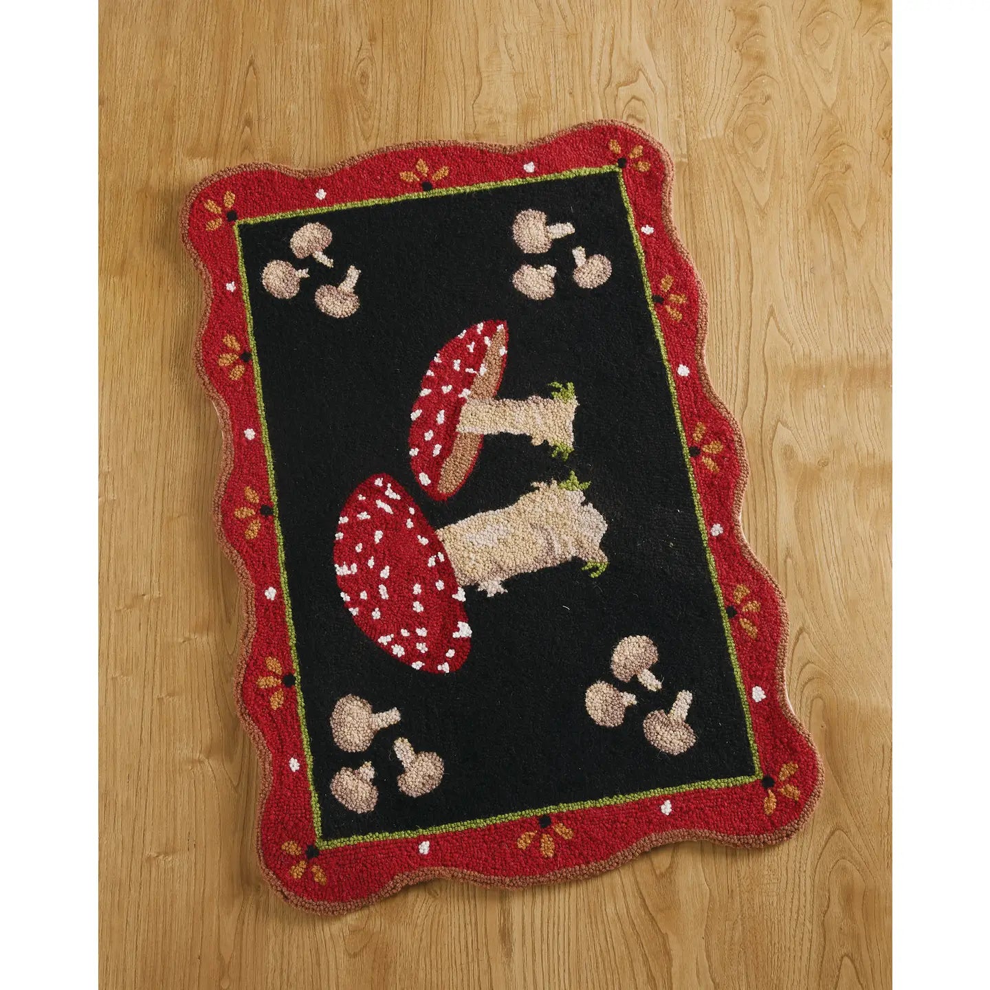 The Peking Handicraft Mushroom Mania Wool Hook Rug is a rectangular black wool rug with a scalloped red border, showcasing red and white mushrooms in the center and smaller mushrooms around, making it an ideal entryway decoration.