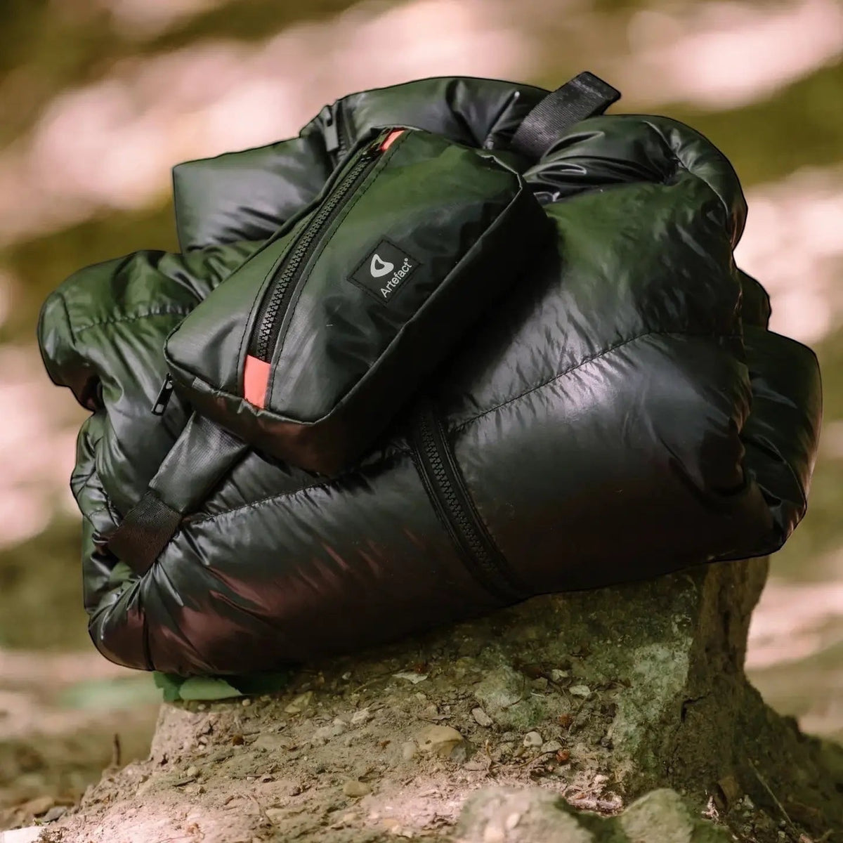 Shop the eco-friendly Artefact Hornbill Banana Sling Bag in black, shown outdoors on a sunlit rock.