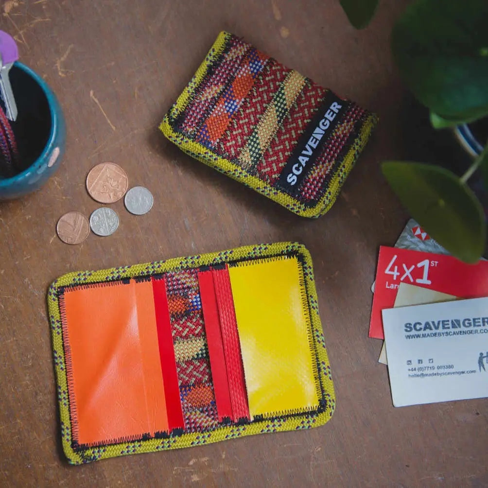 Eco-friendly Scavenger Upcycled Climbing Rope Wallets (Fire) with coins, cards, plant, and cup on wood table.