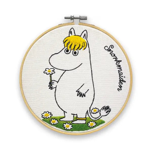 The Crafty Kit Company Snorkmaiden Daisy Cross Stitch kit features the charming Snorkmaiden character holding a flower, surrounded by daisies, with the word "Snorkmaiden" on the side. This delightful embroidery kit makes for a perfect beginner project.