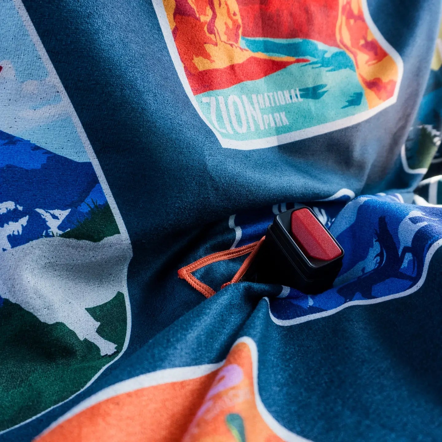 Forager Provisions LTD Sprints National Parks car seat towel with colorful landscape prints and seatbelt buckle.