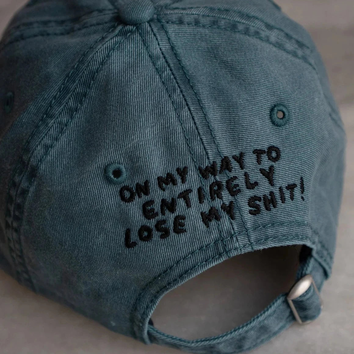 Vintage teal Stay Home Club dad hat with bold black "Lose My Sh**" embroidery on front & back; trendy adjustable cap.