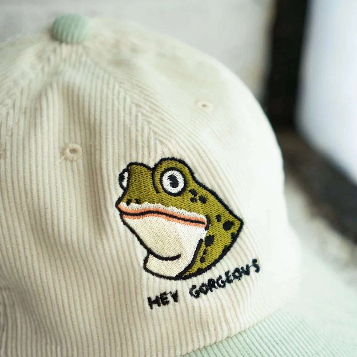 Stay Home Club Hey Gorgeous hat: two-tone corduroy dad cap with embroidered frog face and bold "HEY GORGEOUS" text. Trendy gift.