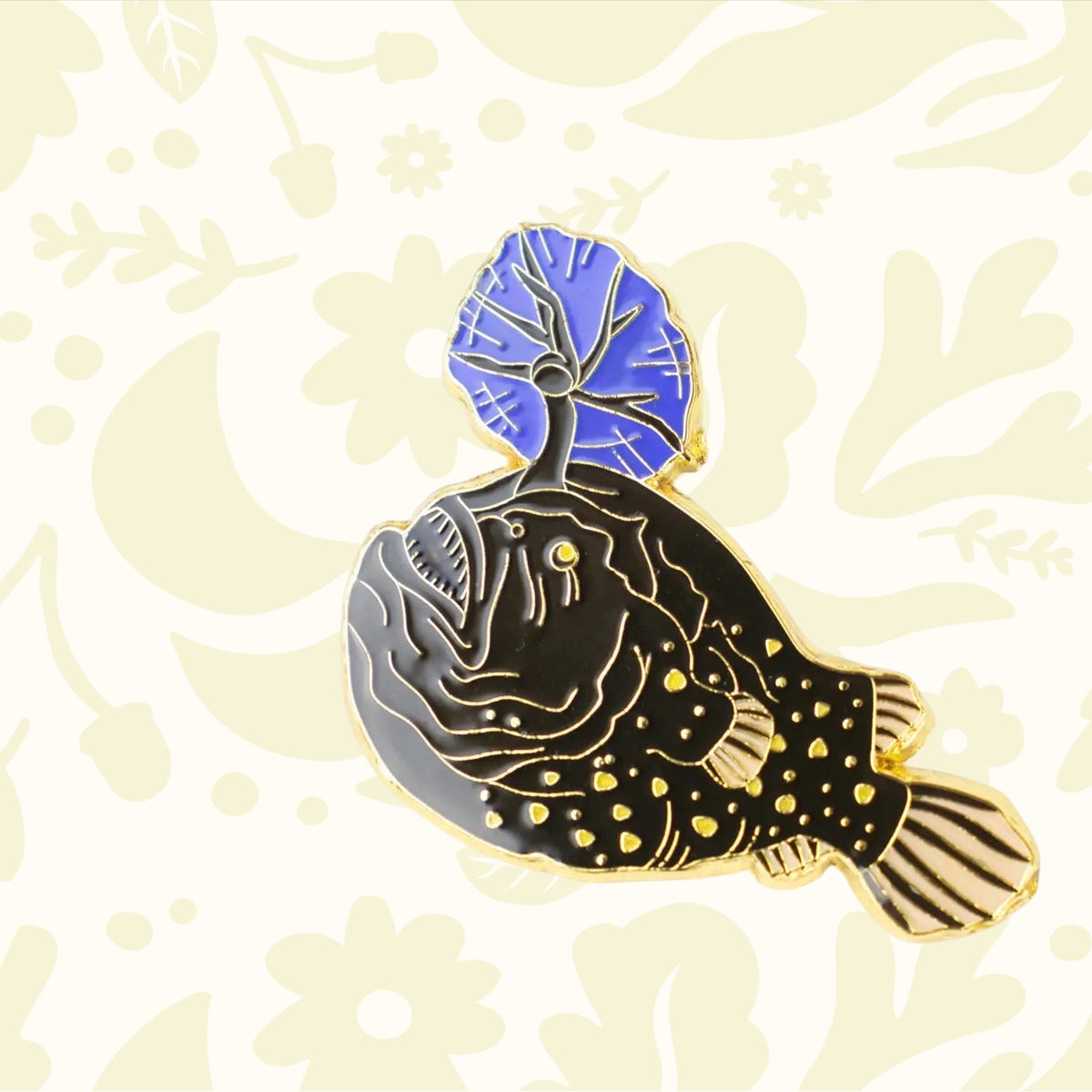 Stemcell Atlantic Football Fish enamel pin—black/gold, blue lure—Japan made. Unique ocean fish lapel pin on white backdrop.