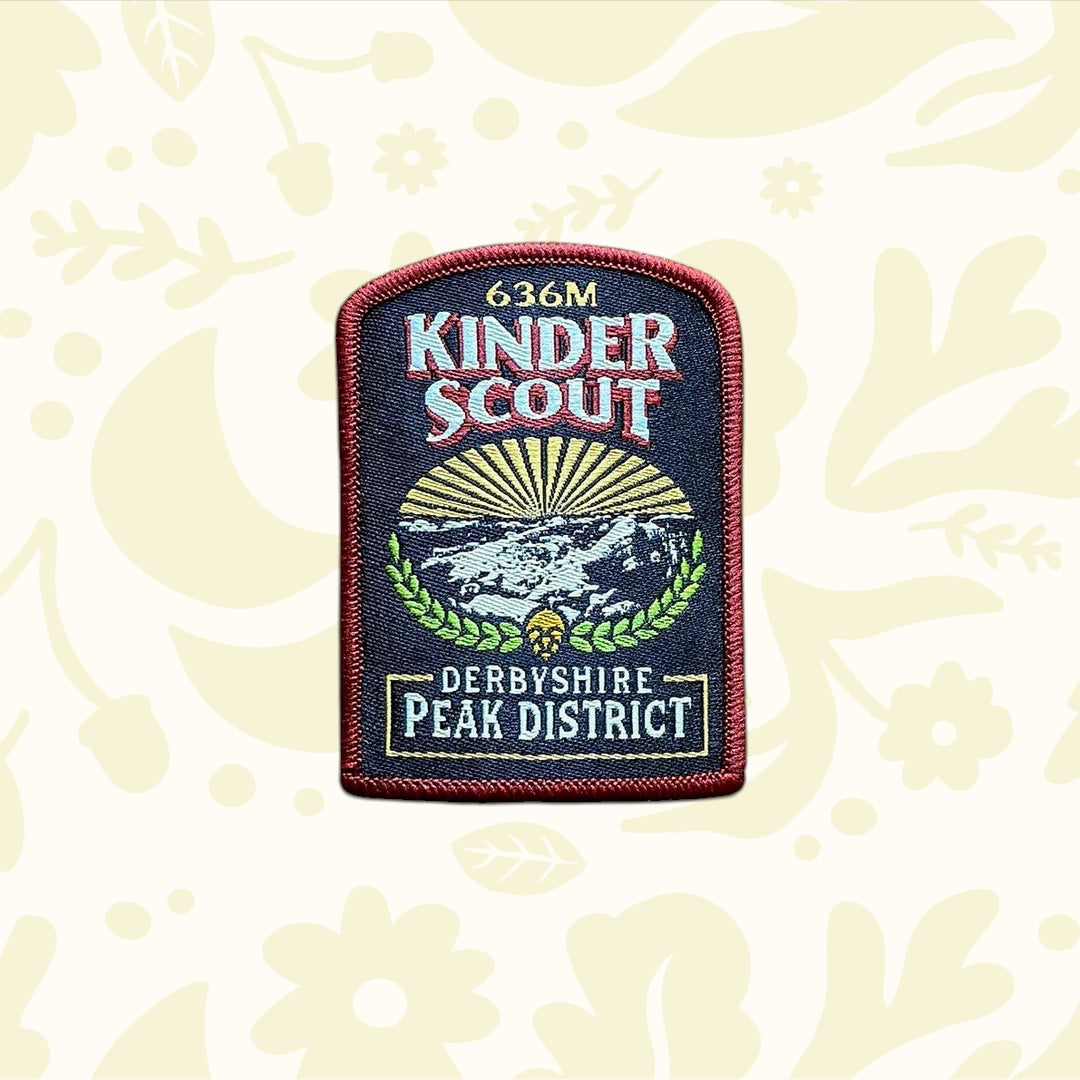 Kinder Scout Patch from The Adventure Patch Company’s Fells Series on rustic scratched wood; embroidered hiking badge.