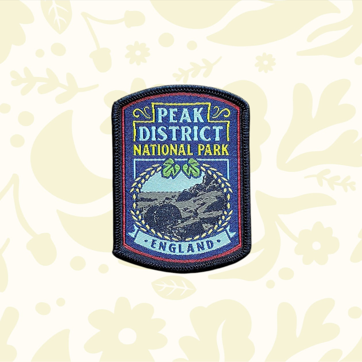 Peak District National Park patch by The Adventure Patch Company with mountain scene and leaves on wood background.