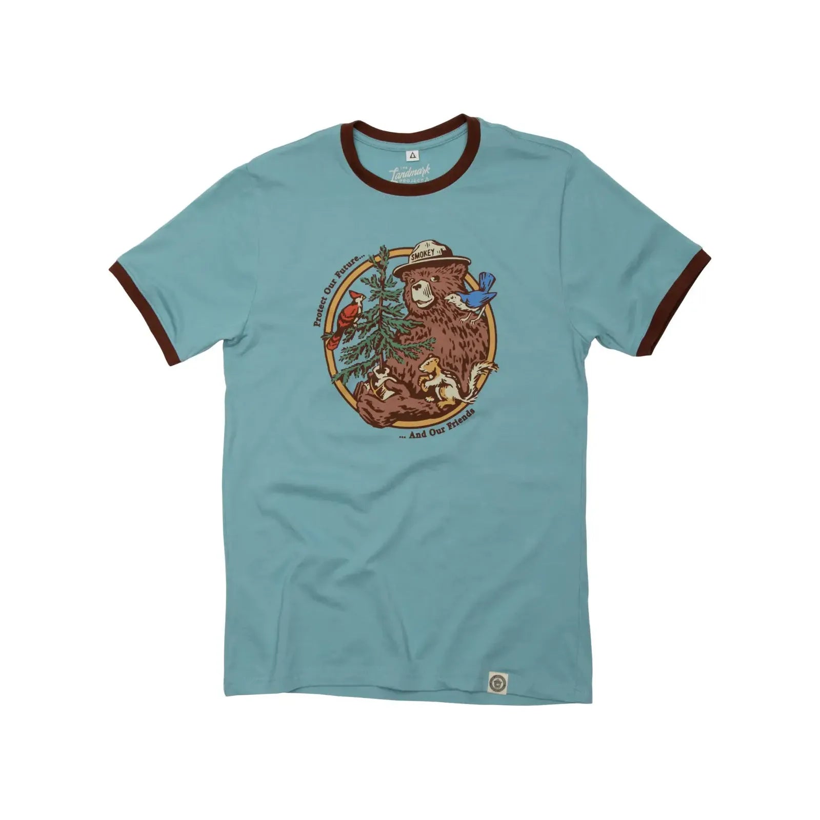 The Landmark Project Ringer Smokey Bear T-Shirt - Glacier is a retro-style blue t-shirt with brown trim, featuring a print of Smokey Bear in a ranger hat, surrounded by animals and a tree. This eco-friendly fashion piece is sustainably made.