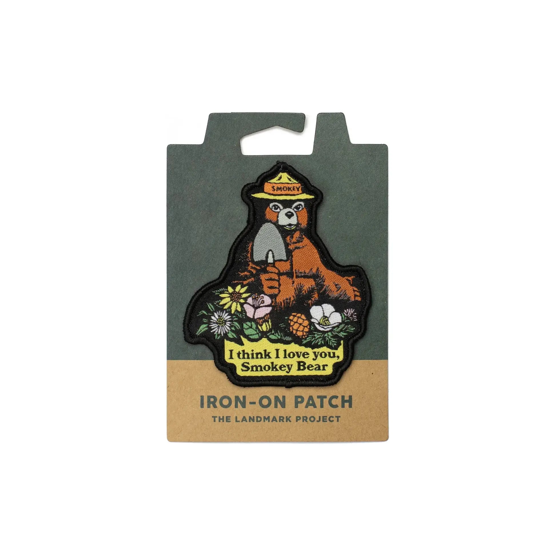 The Landmark Project Smokey Bear Patch - I Love You Smokey, featuring a charming design with flowers and the text "I think I love you. Smokey Bear," is packaged on sustainable cardboard backing. Perfect for outdoor adventures!