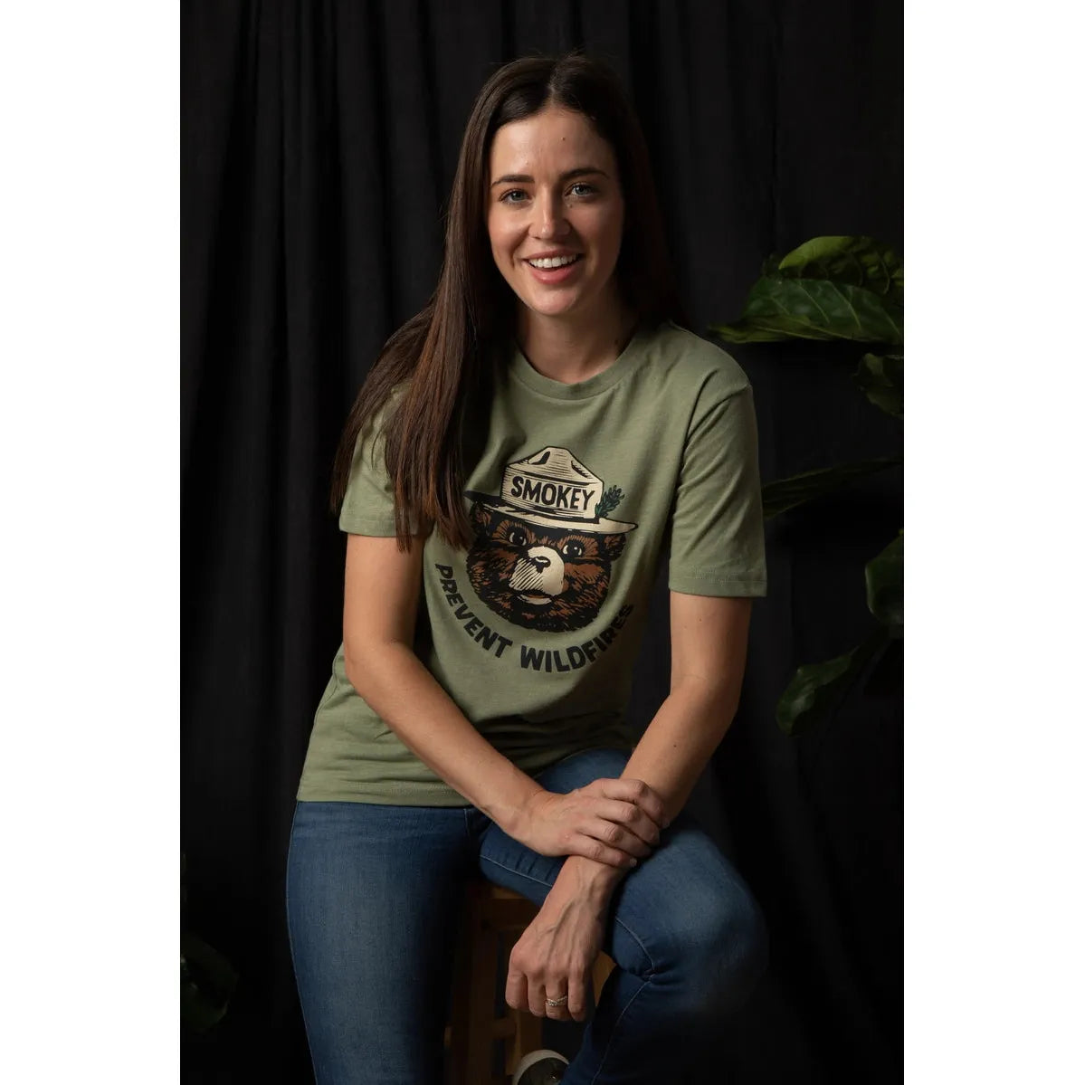 Discover the allure of our cactus green Landmark Project Retro Smokey Bear T-Shirt, showcasing a graphic of a bear in a ranger hat with "Smokey" text and the phrase "Prevent Wildfires" in vintage colors. This sustainably crafted T-shirt seamlessly combines style and purpose.