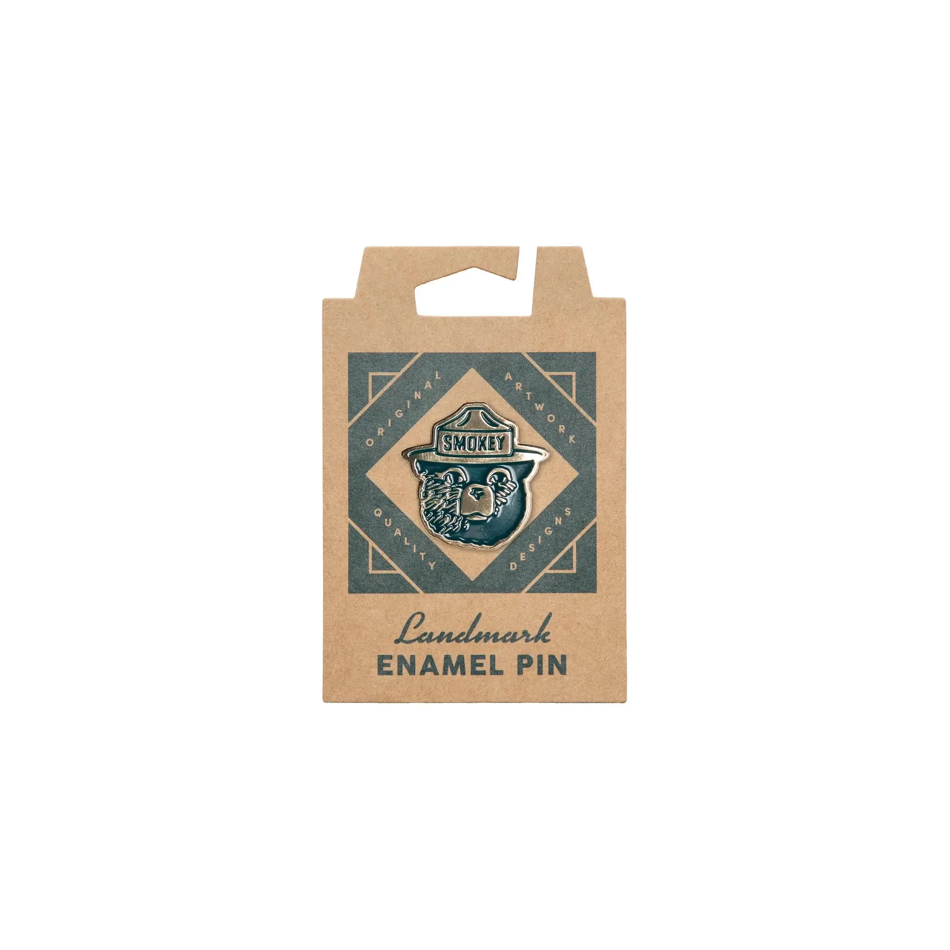 The Landmark Project Smokey Enamel Pin - Smokey Logo packaging features the text "Original Artwork, Quality Designs, Landmark Enamel Pin," on eco-friendly cardboard backing, promoting wildfire prevention.