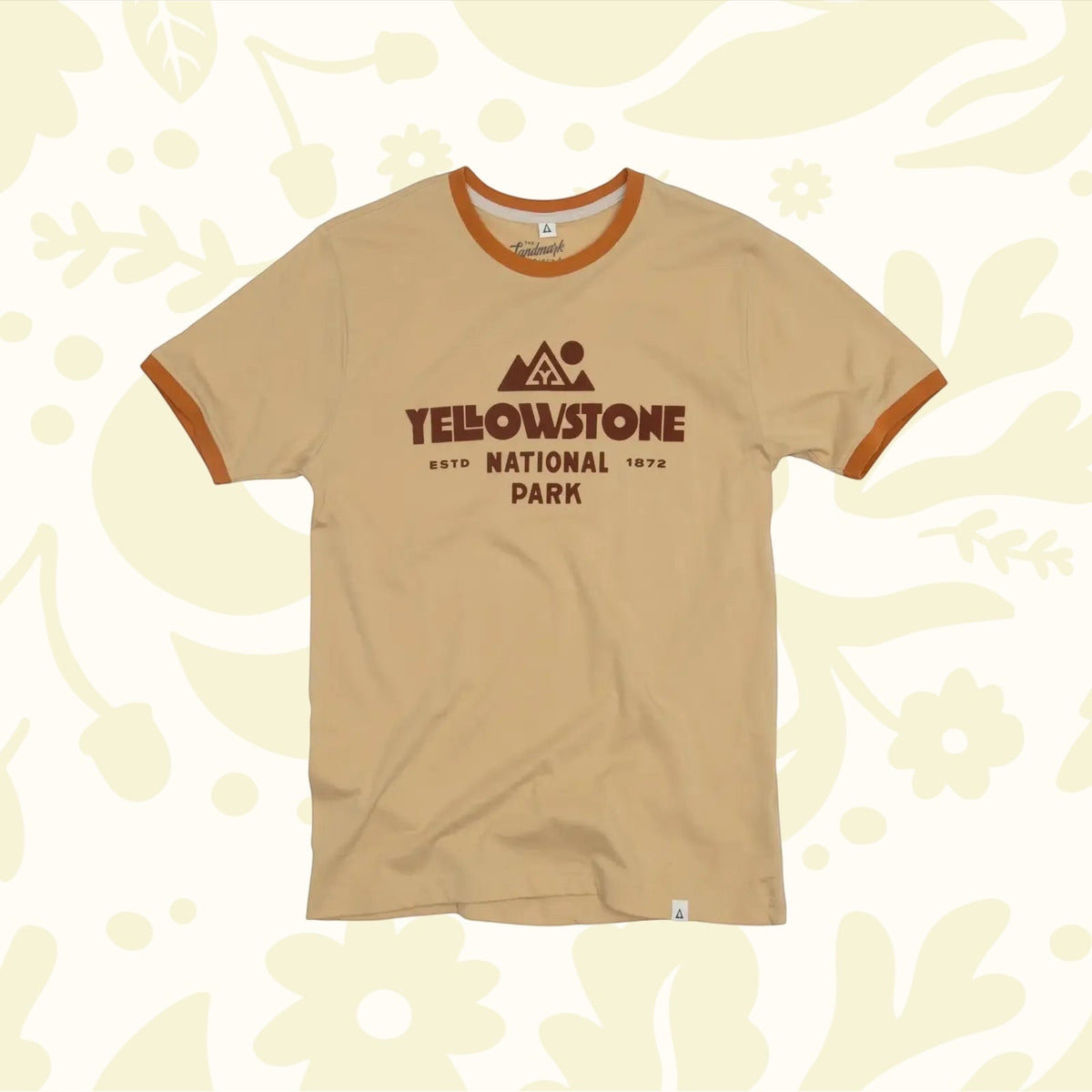 The Landmark Project Yellowstone Type Ringer T-Shirt is a beige tee with orange trim, featuring the text "Yellowstone National Park" and a mountain graphic in brown, sustainably made for eco-conscious adventurers.