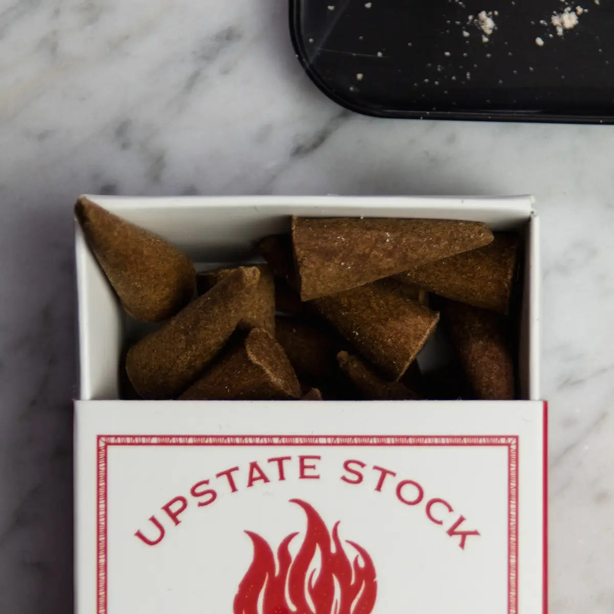 A white box labeled "Upstate Stock Incense Hunter Mountain Red Clover" containing 25 incense cones is displayed on a wooden surface, reminiscent of the herbal remedies found near Hunter Mountain.