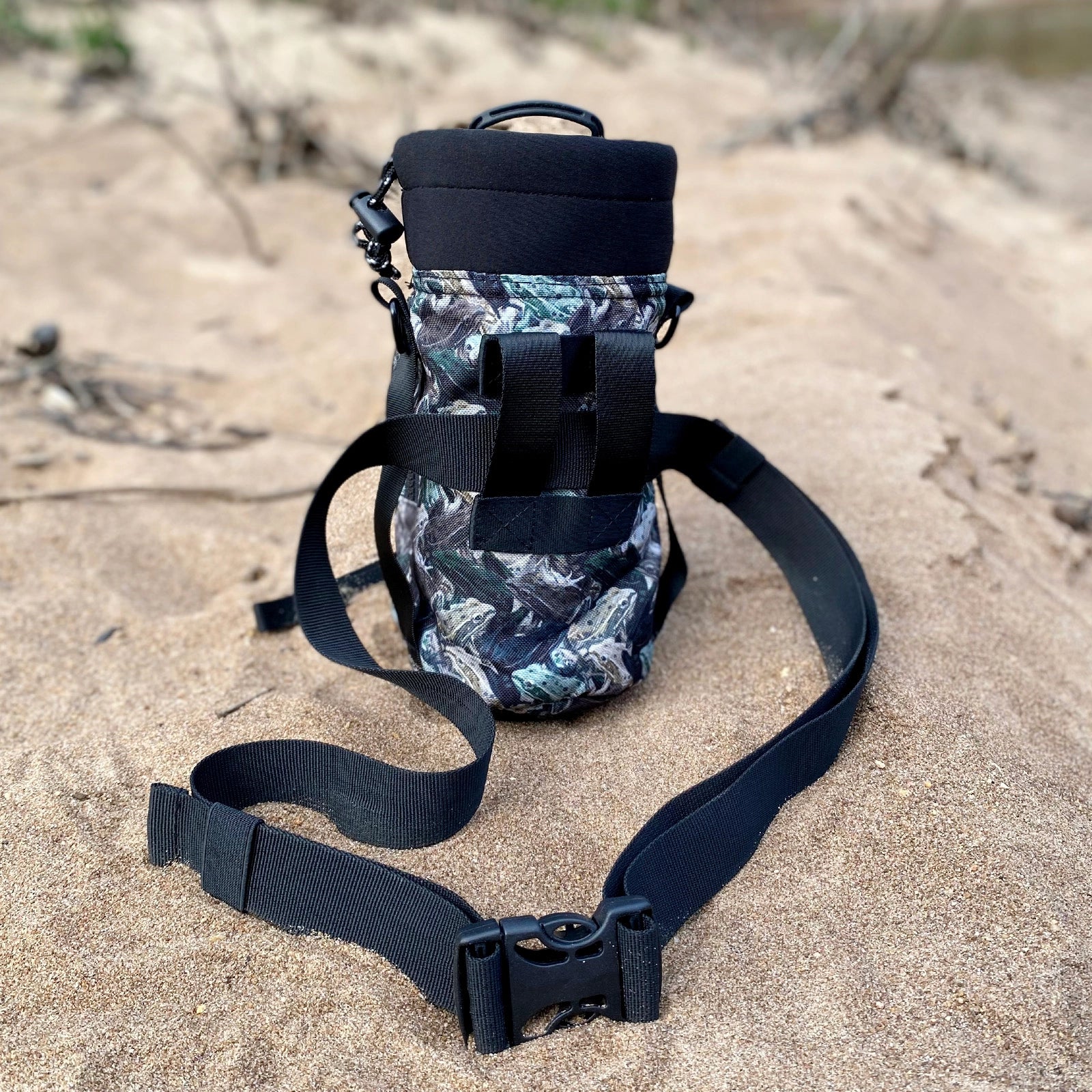 Black Waist harness attached to floral pattern and black  water bottle holder, straps on a sandy surface
