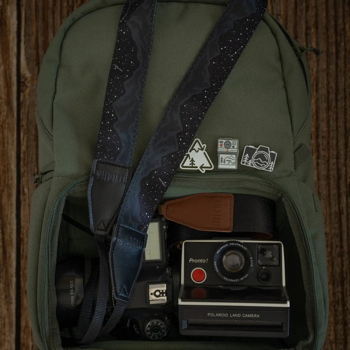 Forager Provisions LTD Midnight Mountain camera strap with starlit peak design inside a green backpack with cameras.