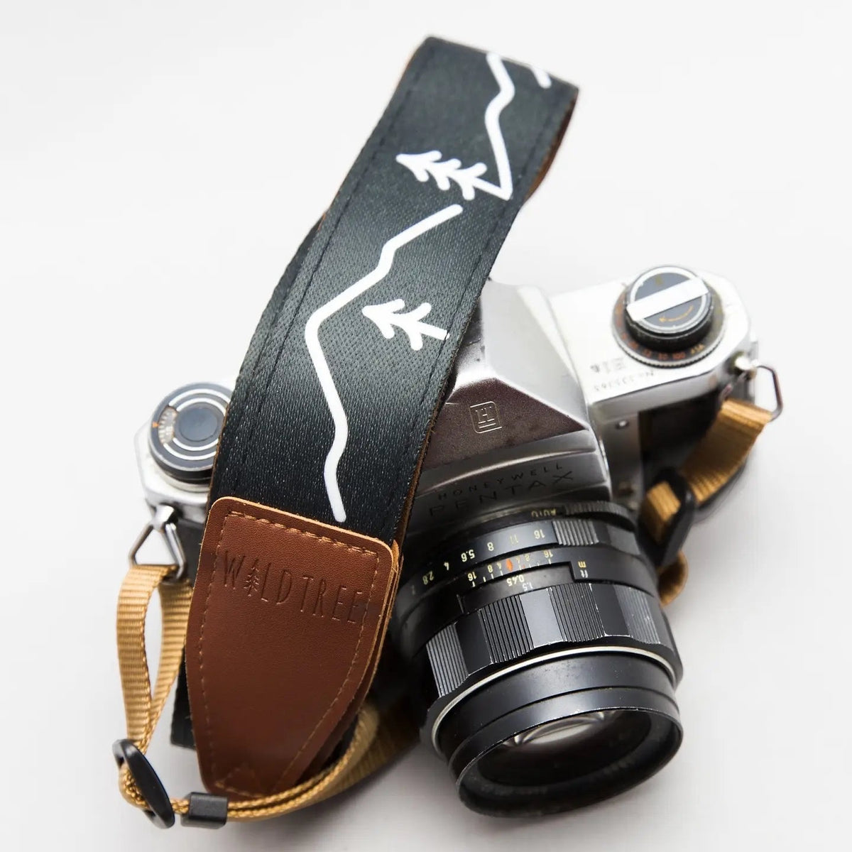 Vintage film camera with Wildtree Simple Mountain strap, tan leather detail, on clean white background photography gear.