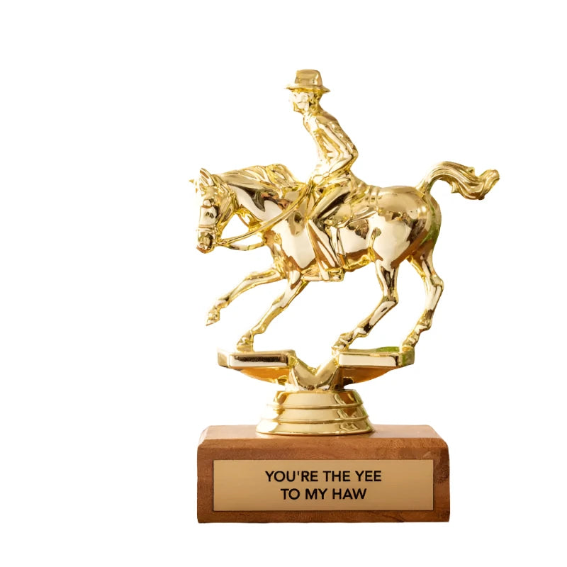 The Jenni Earle Cowboy Trophy - You're The Yee To My Haw features a cowboy on a horse figurine mounted on an FSC certified wooden base, with an inscribed plaque reading "You're the Yee to My Haw," and is presented alongside a blue, cowboy-themed decorative recyclable gift box.