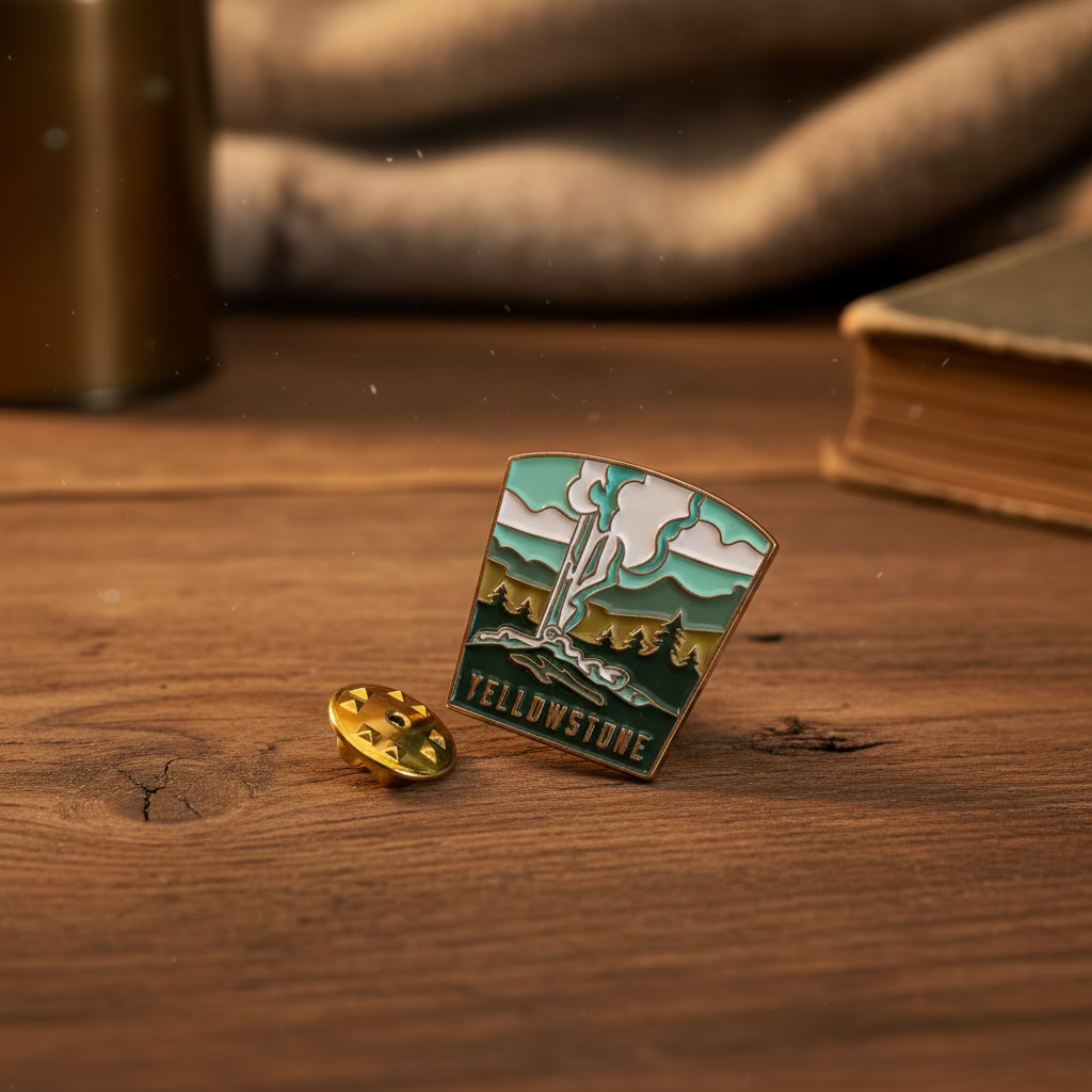 Forager Provisions LTD Yellowstone National Park enamel pin featuring a geyser illustration on a wooden surface