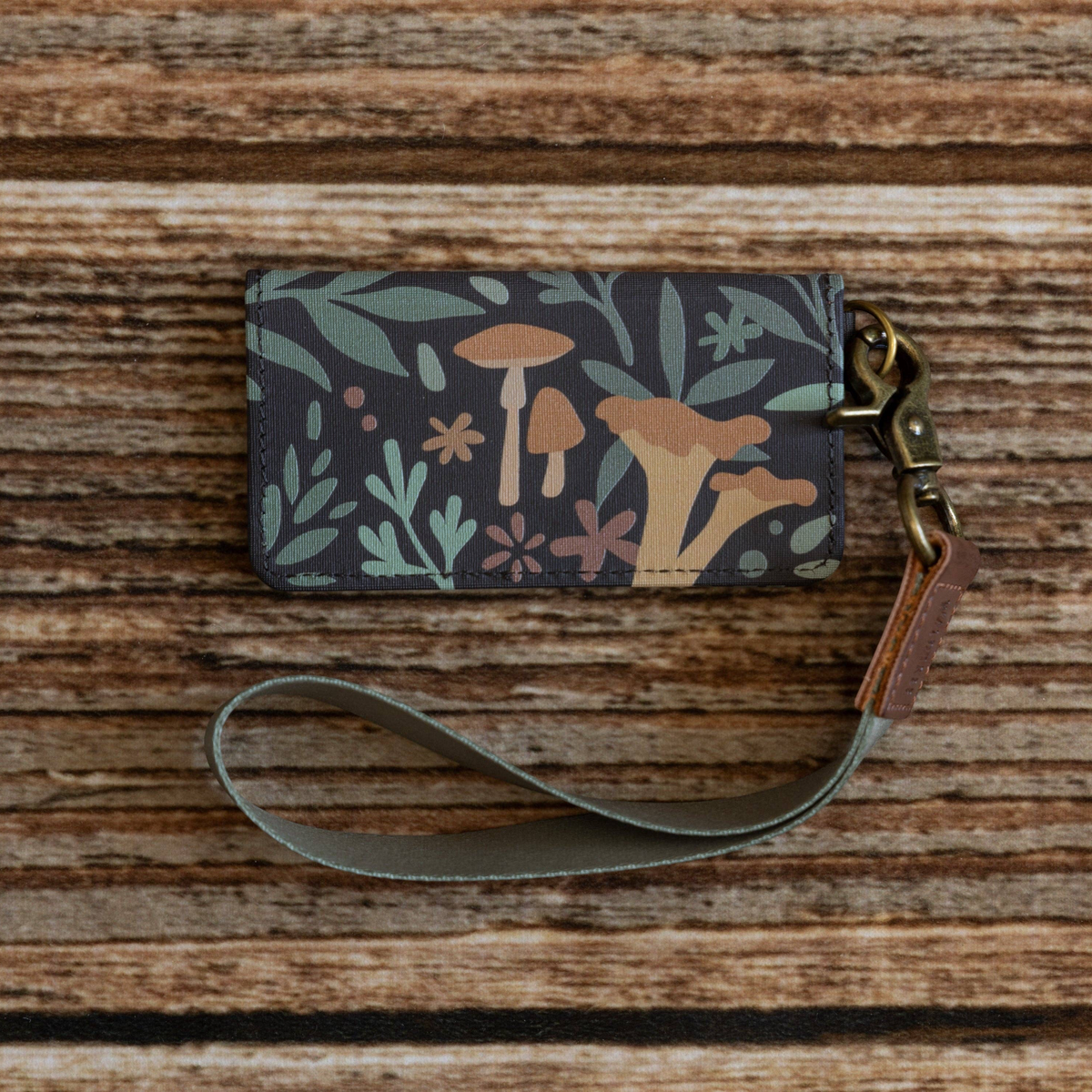 Forager Provisions LTD Wildtree Forest Foliage card holder with mushroom print, brown leather, and wrist strap.