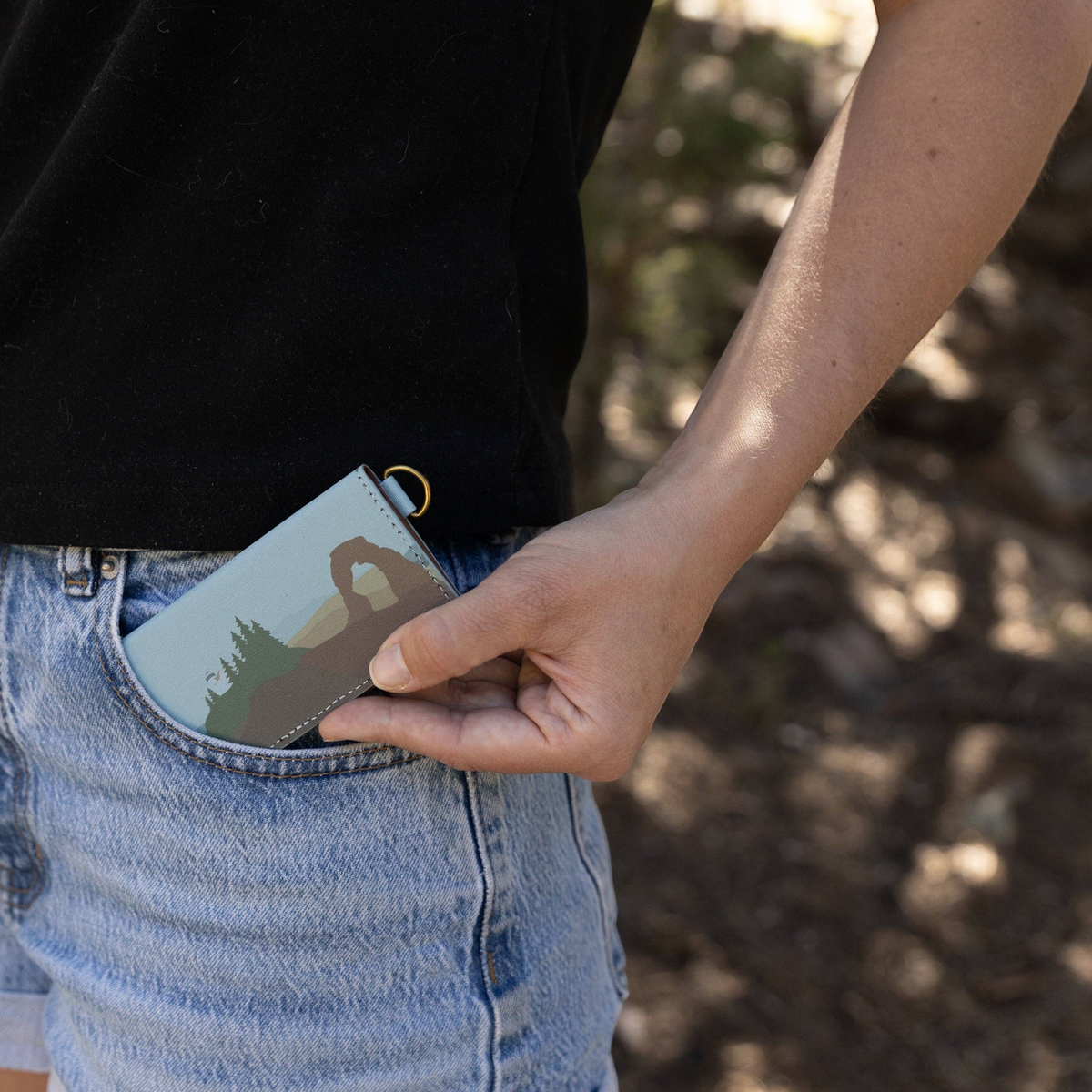 Forager Provisions LTD Wildtree card holder with National Park artwork being placed into a denim shorts pocket