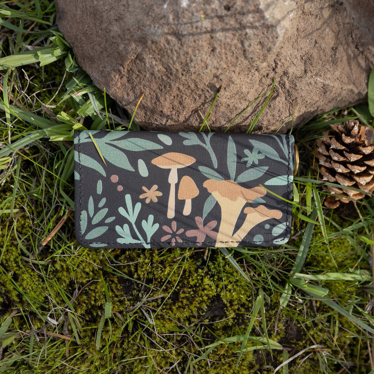 Forager Provisions LTD Wildtree Forest Foliage card holder with mushroom print on a mossy forest floor with a pinecone.