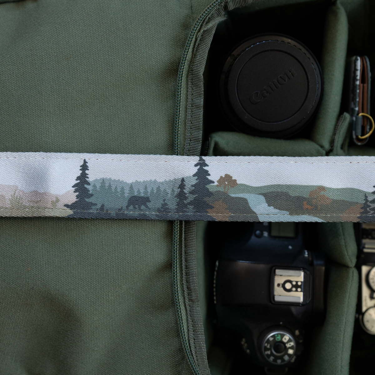 Forager Provisions LTD Wildtree Wildlife Wander camera strap with wilderness landscape print over a green camera bag