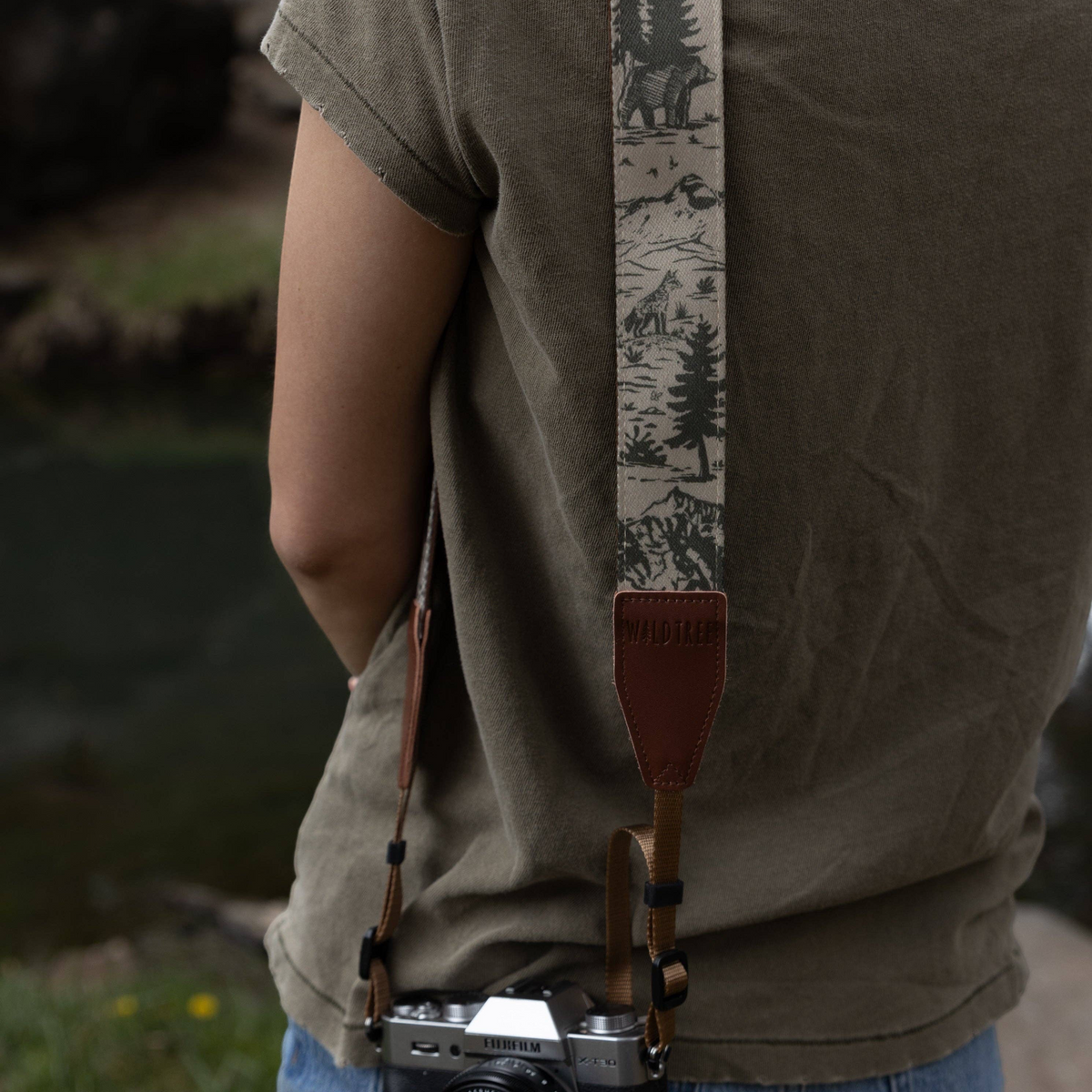 Forager Provisions LTD Wildtree camera strap featuring a woodland mountain print worn over a green t-shirt