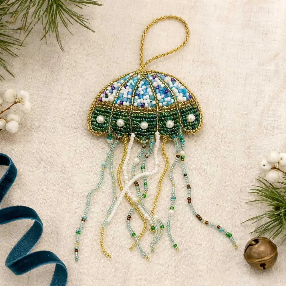 Forager Provisions LTD beaded jellyfish Christmas ornament with blue, green, and gold dangling tentacles on a tree.