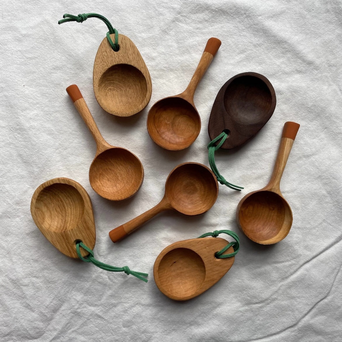 Forager Provisions LTD collection of handcrafted wooden camping coffee scoops with green ties on a white fabric background