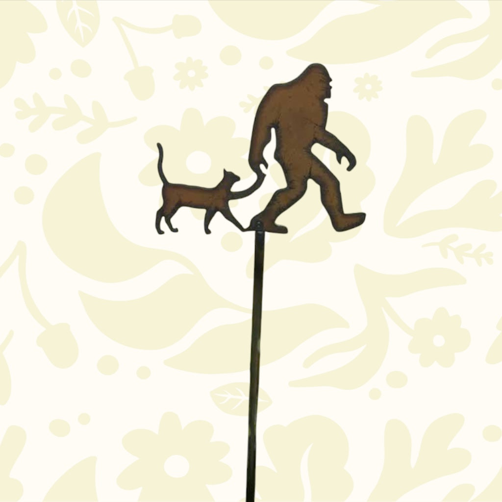 Forager Provisions LTD rustic metal Bigfoot and cat plant stick in a garden bed with green foliage