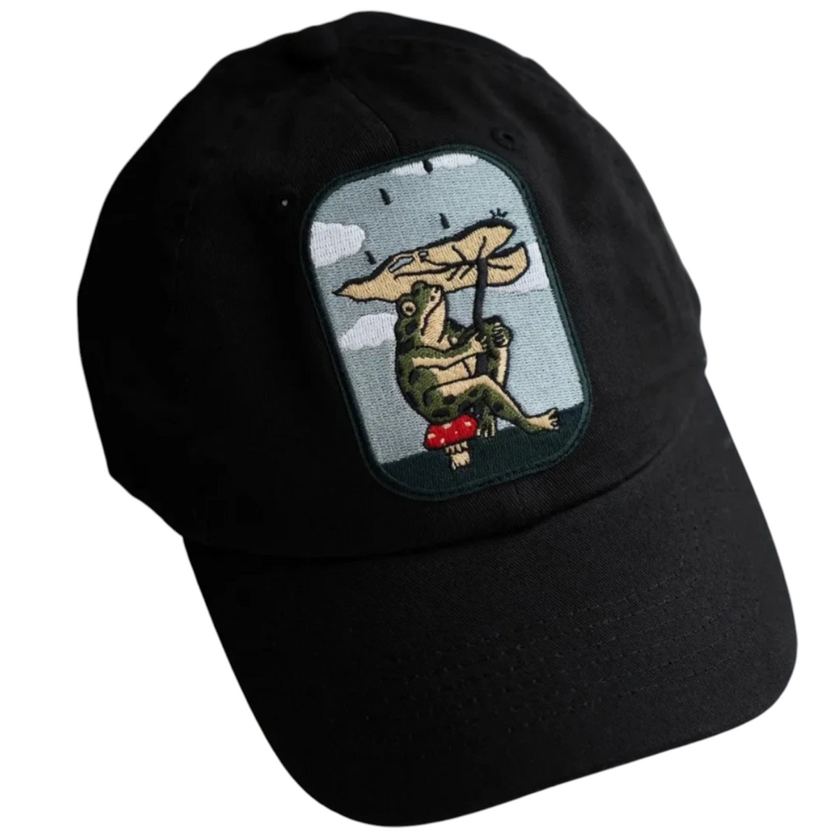 Forager Provisions LTD black dad hat featuring an embroidered patch of a frog holding a leaf umbrella on a mushroom.