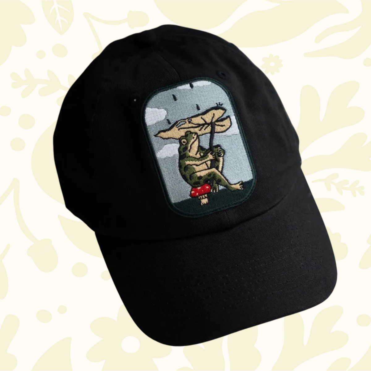 Forager Provisions LTD Stay Home Club black cotton dad hat featuring an embroidered frog with a leaf umbrella patch.