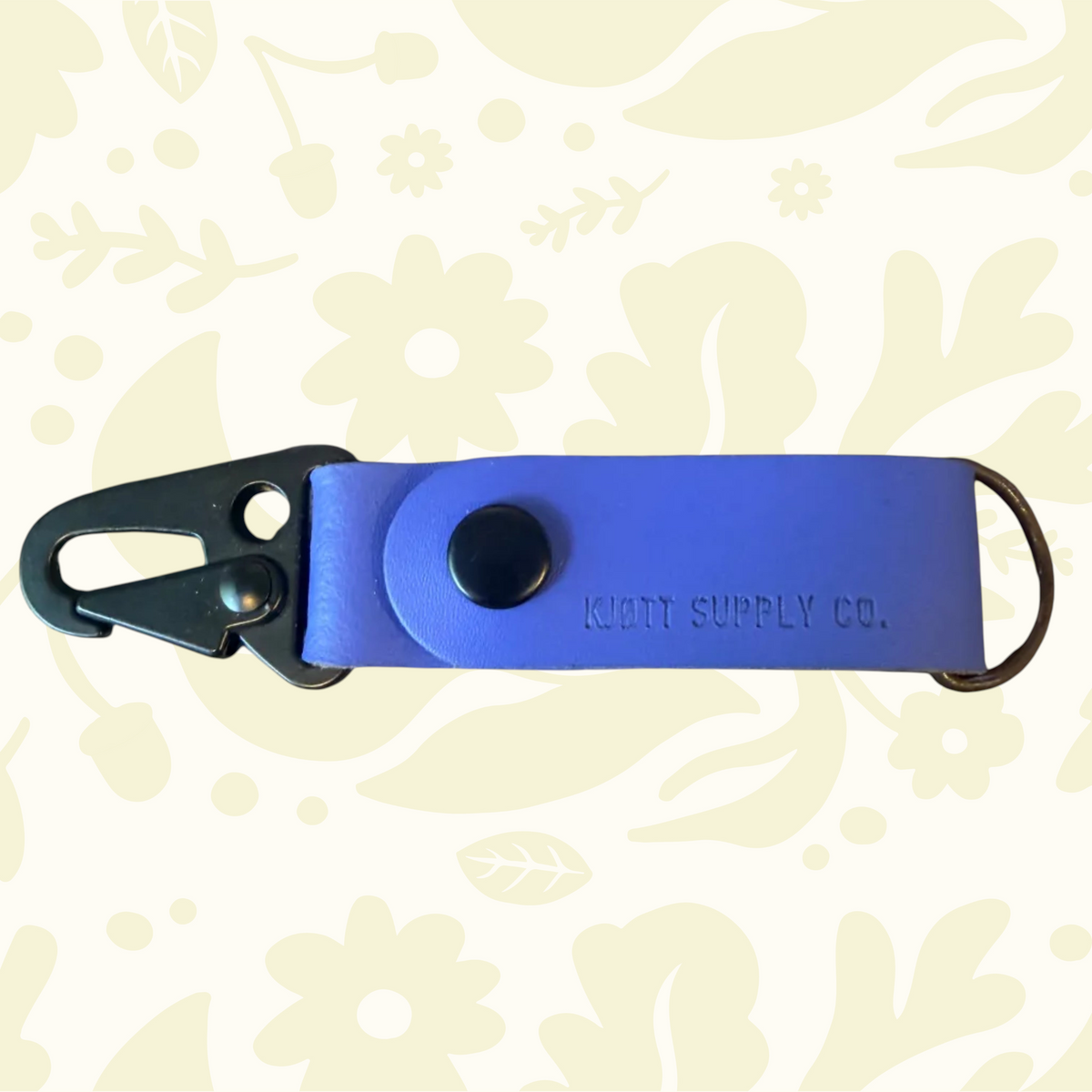 Purple Kjøtt leather key fob, metal clasp, floral embossed design, KNOT SUPPLY CO. logo—luxury accessory for keys.