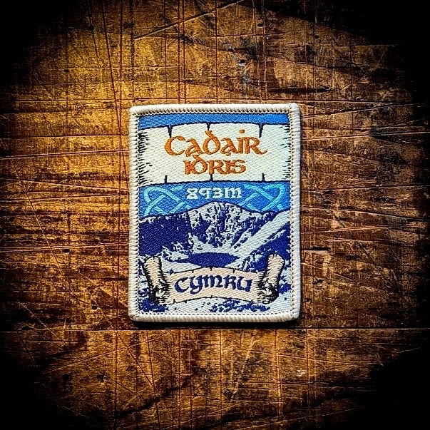 Forager Provisions LTD embroidered Cadair Idris mountain patch featuring blue landscape and Welsh text on wood background