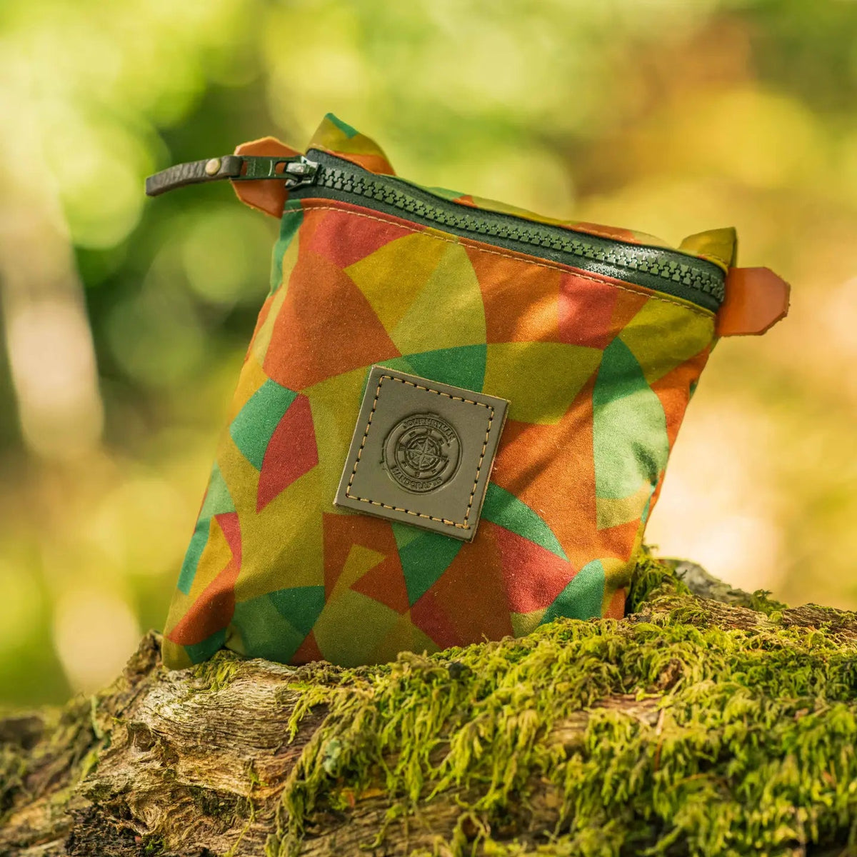 Forager Provisions LTD Journeyman Craft camo zipper pouch made from reclaimed fabric, sitting on a mossy log.