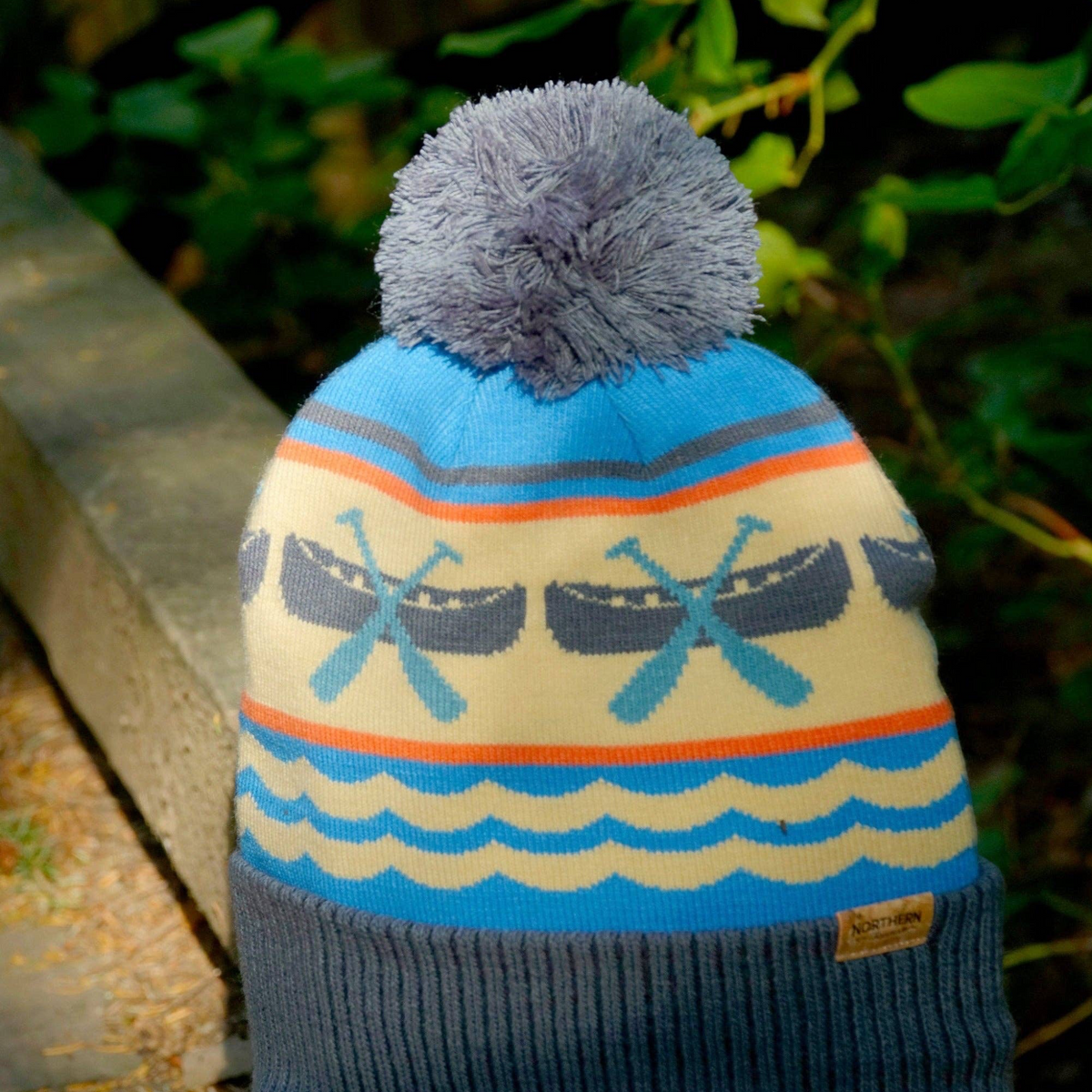 Forager Provisions LTD knit beanie with blue and cream canoe paddle pattern, grey pom pom, and ribbed cuff.