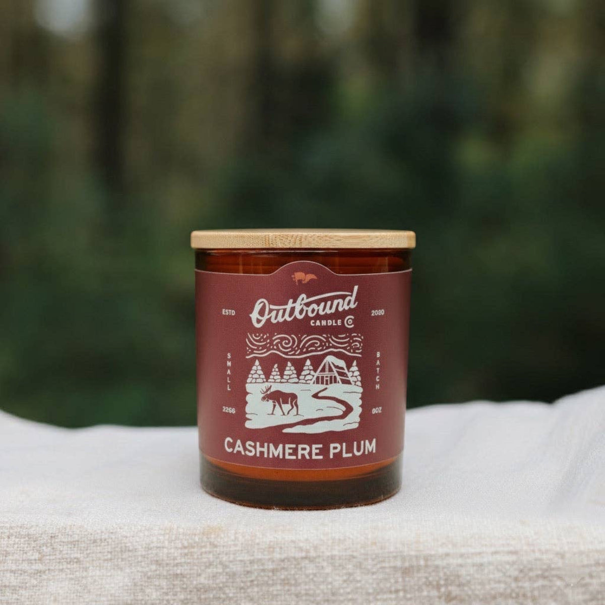 Forager Provisions LTD Cashmere Plum soy candle in an amber glass jar with a bamboo lid, featuring a winter label.