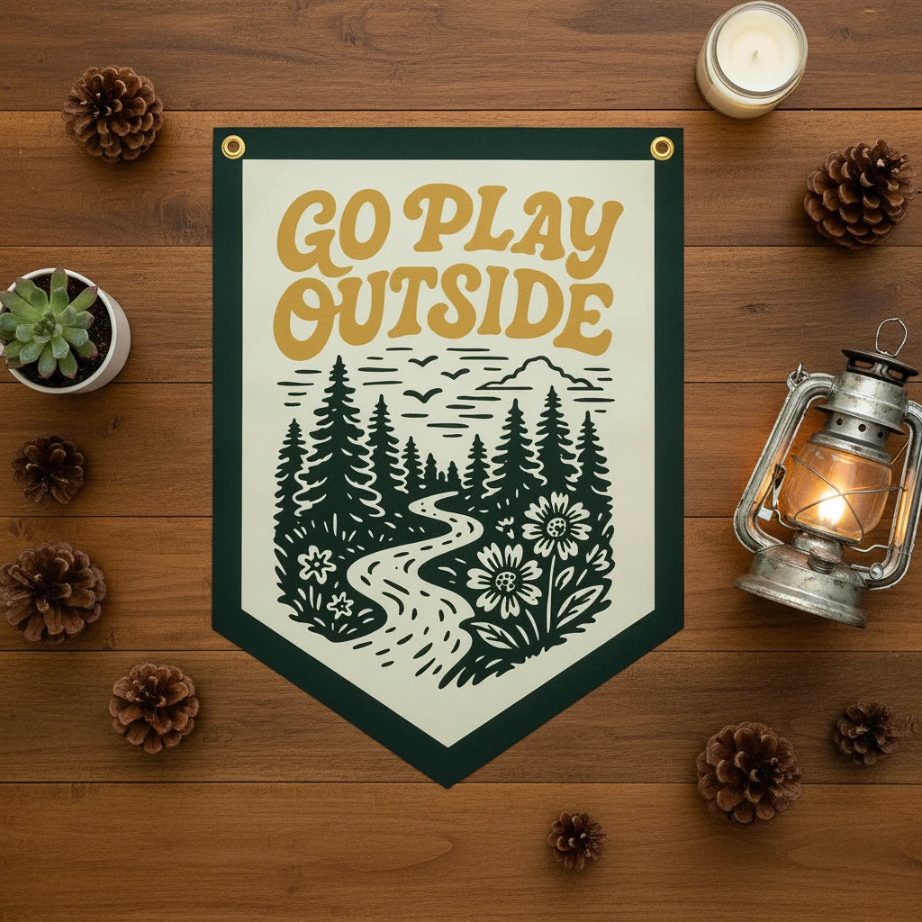 Benoit’s “Go Play Outside” felt camp pennant on table with forest and floral decor, perfect rustic outdoor home accent.