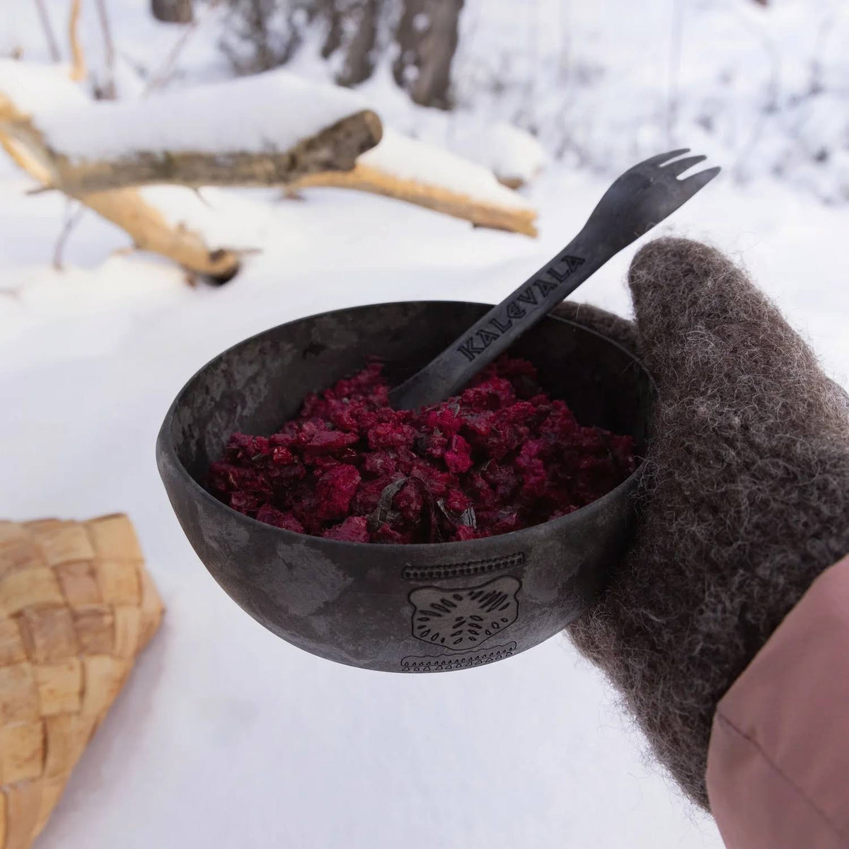Forager Provisions LTD Kupilka 225 long black spork in a bowl of food held by a gloved hand in a snowy outdoor setting.