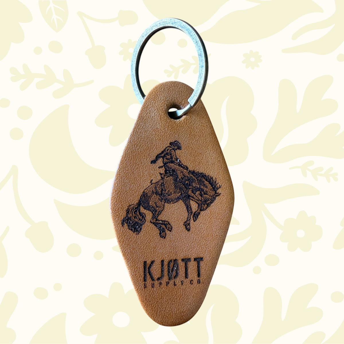 Forager Provisions LTD tan leather motel-style keyring featuring a black stamped bucking bronco and Kjøtt Supply Co logo