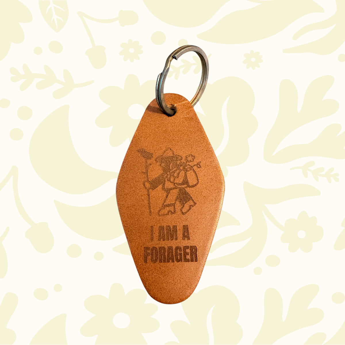 Forager Provisions LTD leather motel-style keyring with I Am A Forager design and metal ring on a stone surface.